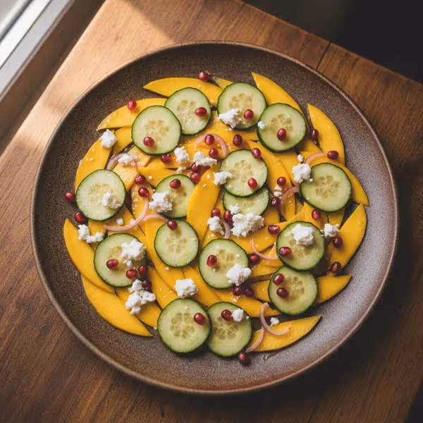 Carpaccio de mango y pepino con queso feta y granada, ya emplatado