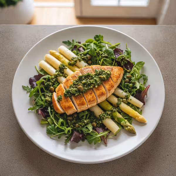 Espárragos y pechuga de pollo sobre mezcla de brotes tiernos con salsa verde, ya emplatado